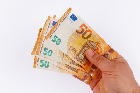 An engaging overhead shot capturing a hand holding several 50 euro bills against a clean white backdrop, symbolizing wealth and financeの写真素材