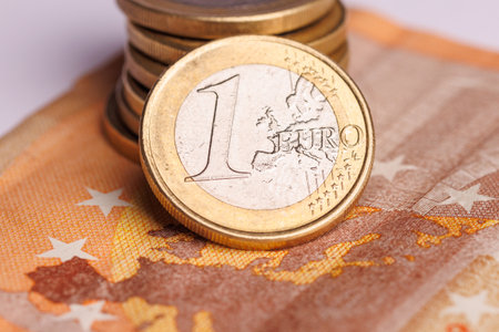 A 50 euro bill is showcased beneath a mountain of 1 euro coins, illustrating the significance of different denominations in financeの写真素材