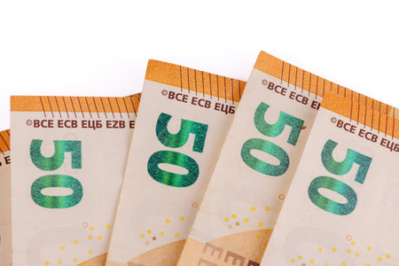 An artistic overhead shot showing multiple 50 euro bills elegantly fanned out against a clean white...