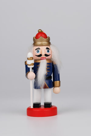 A cheerful wooden nutcracker, showing its original hair, stands out against a clean white...