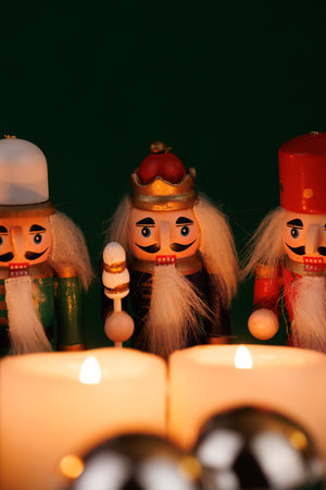 This playful nutcracker, adorned with original hair, is set against a bright green background with lit candles and Christmas ornamentsの写真素材
