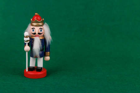 A joyful wooden nutcracker with original hair stands out against a lush green background, embodying the festive spirit of the seasonの写真素材