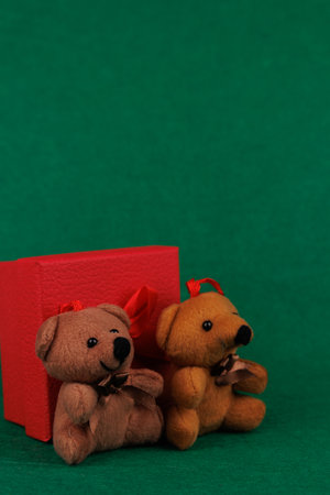 An elegant display of a nutcracker and teddy bear beside a red gift is enhanced by shiny silver ornaments and festive pine cones on greenの写真素材