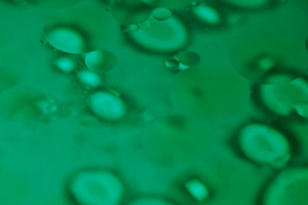 Vibrant oil droplets interact with water, creating abstract and flowing patterns that evolve and shift in real time.の写真素材