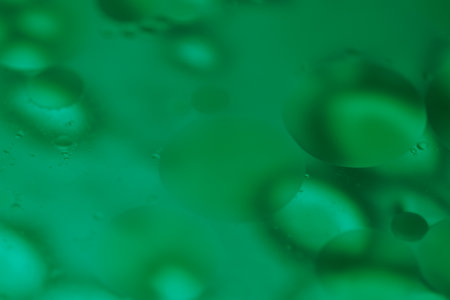 abstract background of water drops on the water surface with green lightの写真素材