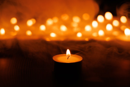 A single candle glows brightly, surrounded by softly blurred lights, creating a peaceful Holy Week sceneの写真素材