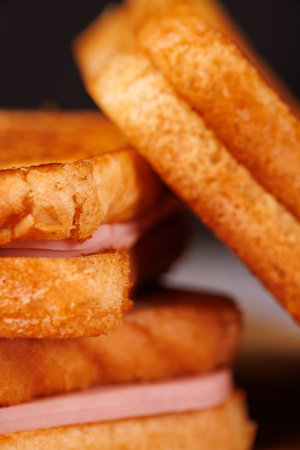 A tempting display of cheese and ham sandwiches alongside fresh cherry tomatoes, beautifully arranged on a concrete table with a black backgroundの写真素材