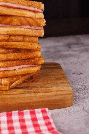 A mouthwatering display of ham and cheese sandwiches stacked vertically, beautifully arranged on a...