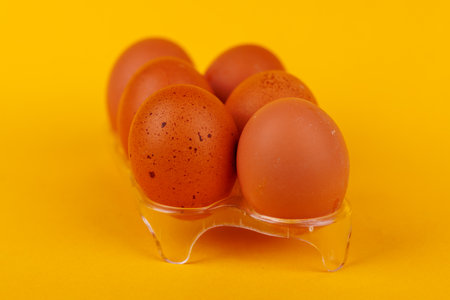 Six Brown Eggs on a Yellow Surface