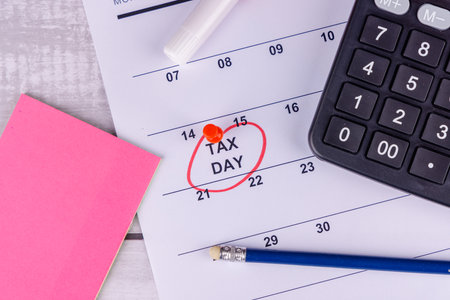 April 15 tax reminder with 1099 form, calculator, and pencil on wooden backgroundの写真素材