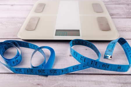 Health Monitoring Tools: Digital Scale and Measuring Tape on Minimalist White Wooden Table