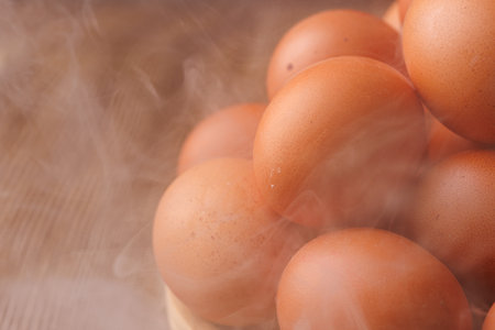 A plate of eggs covered in thick fog on a dark wooden table.の写真素材