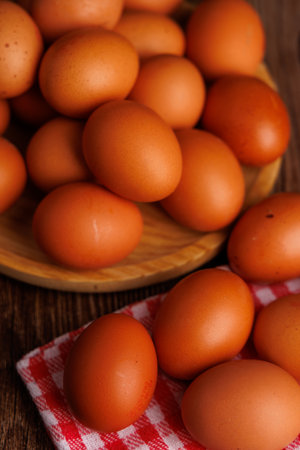 Close-up shot of fresh eggs in a wooden plate, arranged on a rustic table, depicting the increase in...