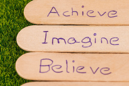 Carved messages of encouragement such as imagine, dream, and achieve set on a grass sceneの写真素材