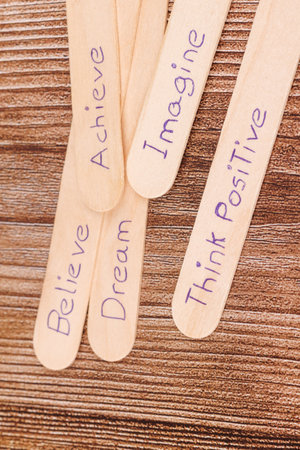 Inspiring words on wood sticksâ€”dream, believe, imagineâ€”lay across a natural wood...