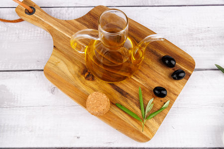 Green and black olives with olive oil bottle and olive sprigs on a rustic wooden cutting board.の写真素材