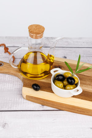 Olive oil bottle with assorted olives and olive sprigs arranged over a wooden board.の写真素材