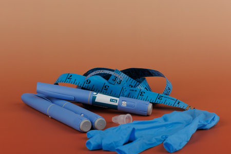 Blue gloves, measuring tape, and injection pens on brown gradient background. Concept image for weight loss treatment and diabetes care.の写真素材
