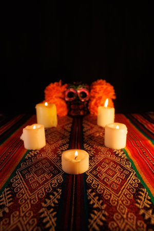 Glowing candles, floral metal-adorned black skull, and magnolia flowers create a colorful Day of the...