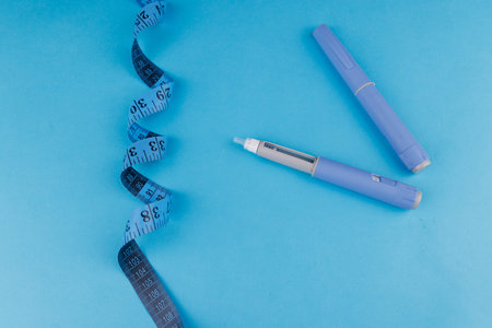 Healthcare and wellness flat lay with semaglutide pens and blue tape measure on intense blue surface