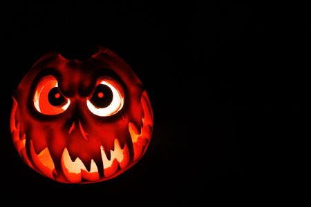 Glowing Halloween pumpkin lantern with terrifying expression in dark.の写真素材
