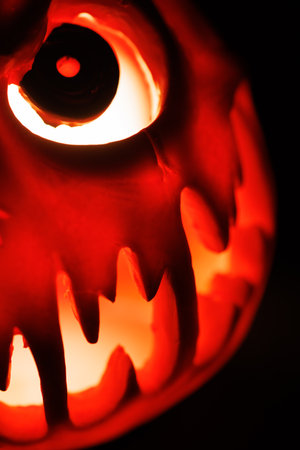 Scary glowing pumpkin lantern with frightening face in darkness.の写真素材
