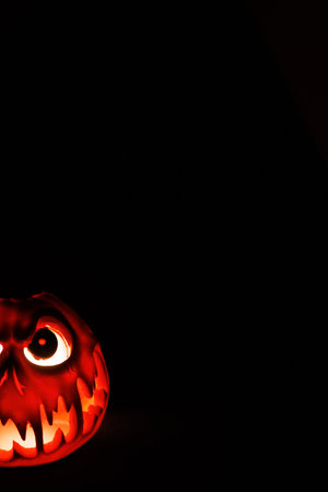 Terrifying Halloween pumpkin glowing with sinister light in dark setting.の写真素材