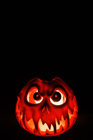 Scary pumpkin lantern glowing bright in dark background.の写真素材