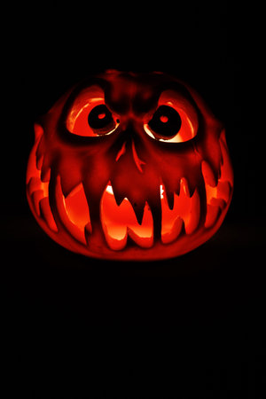 Creepy Halloween lantern carved with scary face illuminated from within.の写真素材