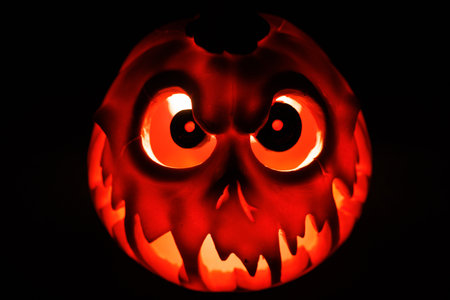 Spooky pumpkin lantern glowing orange in eerie dark background.の写真素材