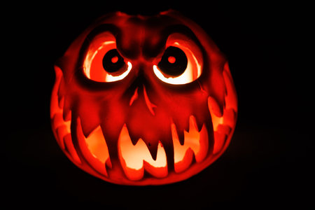 Halloween pumpkin carved with scary face glowing in dark scene.の写真素材