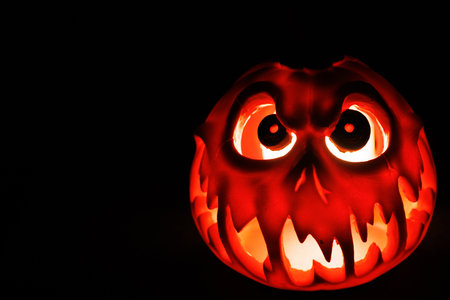 Scary Halloween lantern pumpkin glowing orange in dark.の写真素材