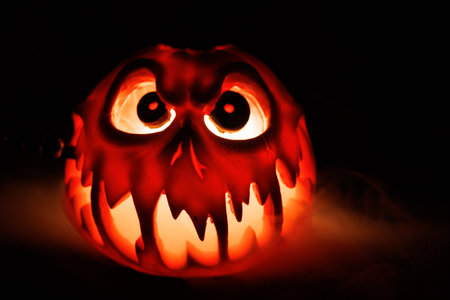 Halloween jack o lantern glowing with smoke in spooky darkness.の写真素材
