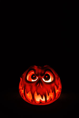 Scary carved pumpkin lantern shining from inside on a black background.の写真素材