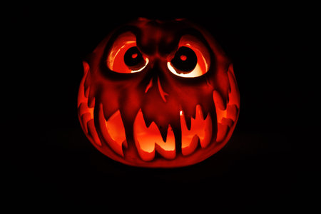 Frightening Halloween pumpkin with glowing carved face in darkness.の写真素材