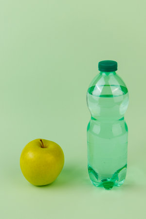 Balanced diet concept with green apple and water bottles on light green surfaceの写真素材