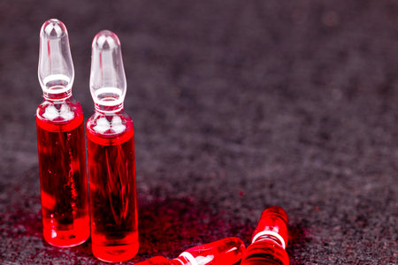 Red vitamin B12 injectable ampoules displayed on black surface for health and wellness