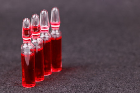 Artistic arrangement of red B12 ampoules on dark background for health careの写真素材