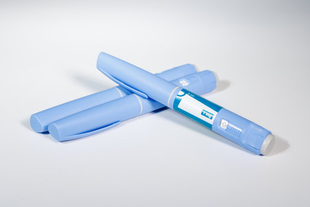 Healthcare arrangement featuring blue pens, blue tape and pill bottle on white background...