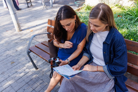 Smiling women share a friendly chat while checking the map and planning their sightseeing day in the...