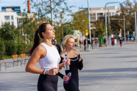 Two friends in sporty outfits jog through the park, enjoying exercise in nature.の写真素材
