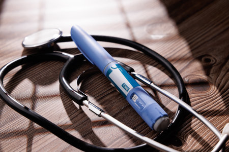 Close up of semaglutide GLP-1 medication pens with a stethoscope on dark wood showing subcutaneous injection therapy for medical and wellness industryの写真素材