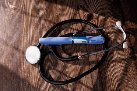 Professional image of GLP-1 medical pens and a stethoscope on a dark wood surface illustrating the treatment of obesity and type 2 diabetes mellitusの写真素材