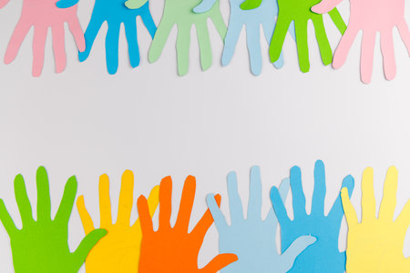 A frame made of colorful paper hand cutouts on a white surface providing a creative space to promote equality and dignity for Human Rights Day 2025.の写真素材