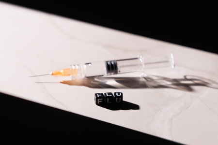 Professional glass syringe for flu immunization on luxury marble surface with sharp light reflections and deep black background for medical themes.の写真素材