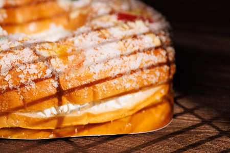Exquisite Three Kings Day cake on a dark wood table. This traditional dessert features a soft dough and vibrant candied fruits for holiday feasts!!の写真素材