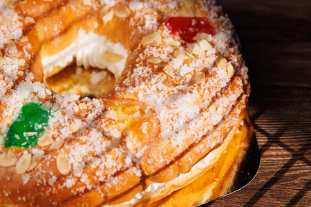 Authentic Spanish Epiphany pastry on a dark wood surface. This seasonal cake with candied fruits and sugar is a staple of January 6th celebrations.の写真素材