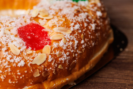Delicious Roscon de Reyes cake with colorful candied fruit on a wooden surface and black background, perfect for Epiphany holiday food celebrations!!の写真素材