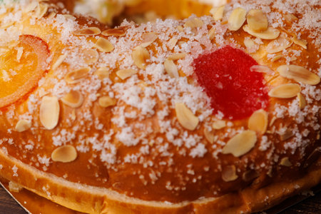 Traditional Roscon de Reyes pastry on a dark wood table. This seasonal dessert is decorated with candied fruits for the Three Kings Day celebration.の写真素材