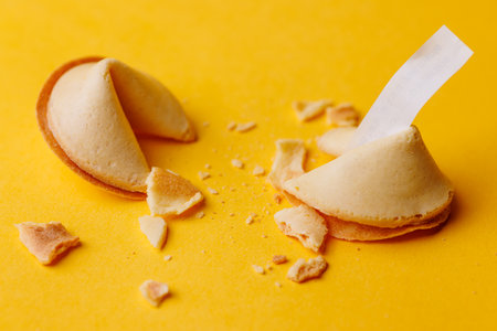 Golden crispy fortune cookies on a vibrant yellow surface. This iconic snack is perfect for representing destiny and cultural celebrations now!!の写真素材